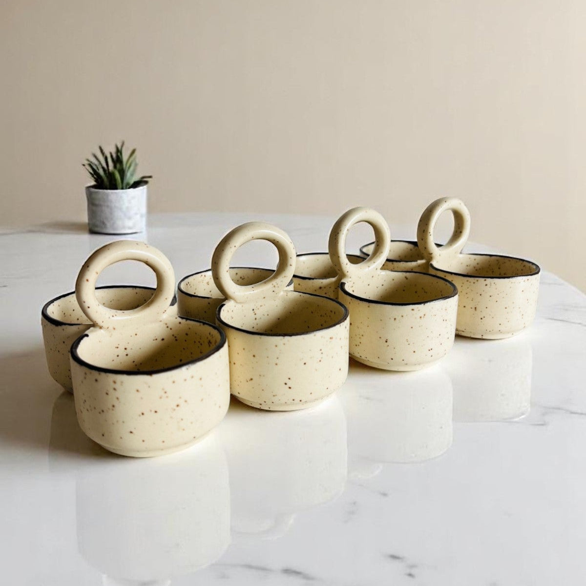 Set of ceramic cups with ring handles on a marble surface